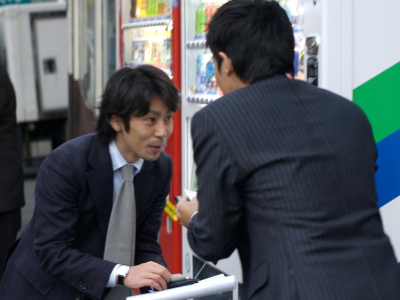 Two Japanese businessmen are engaged in the exchange of business cards in a Japanese tradshow